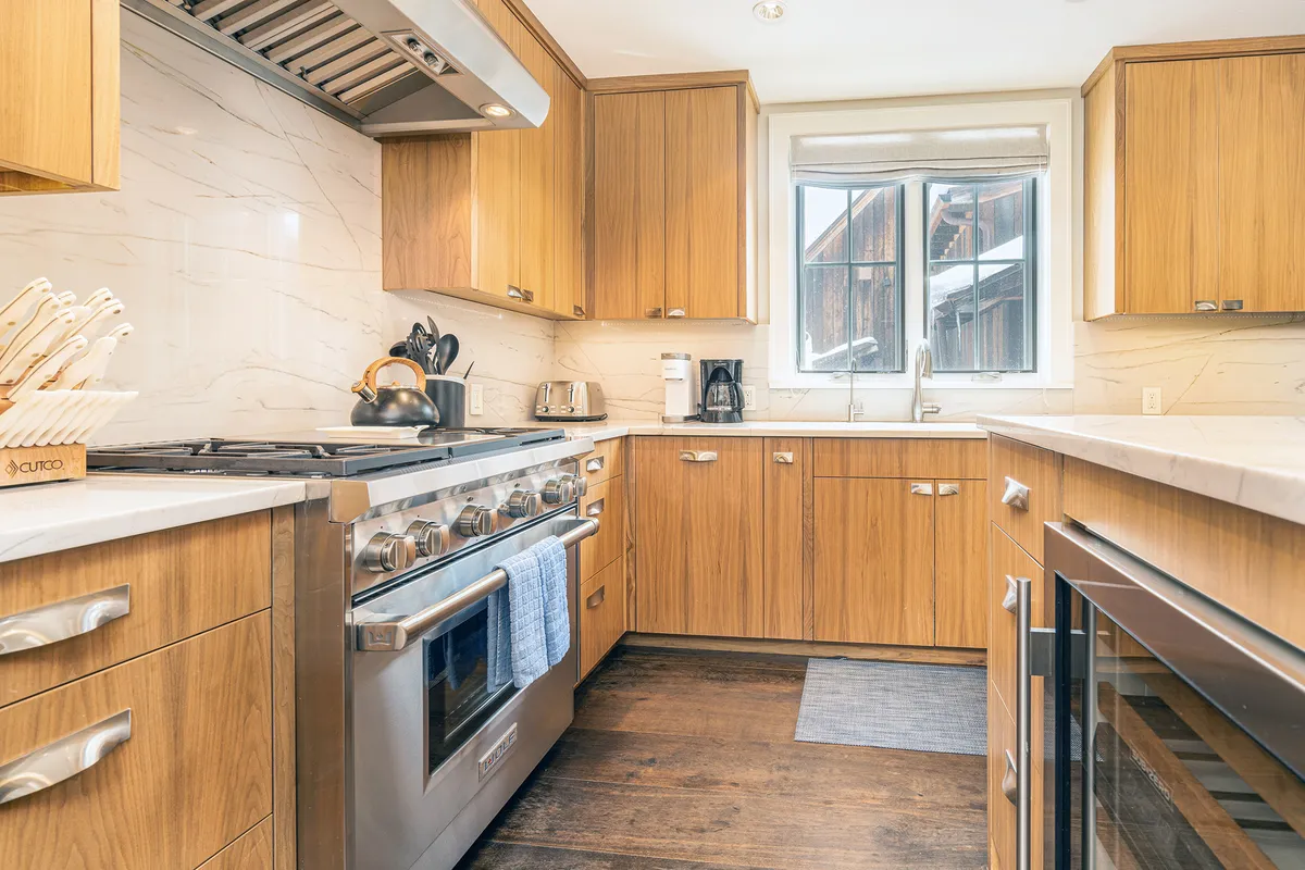 A warmly lit kitchen with stainless steel appliances, wooden cabinets, and a sunlit window. The space looks ready for cooking, baking, or hosting, and feels inviting for both everyday meals and special occasions.