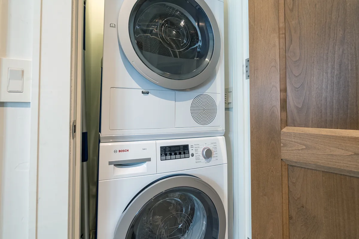 A dedicated laundry area with a washer, dryer, and control panel, captured in a clean and purposeful setting. The space emphasizes the convenience of in-unit laundry for keeping clothes and gear fresh.